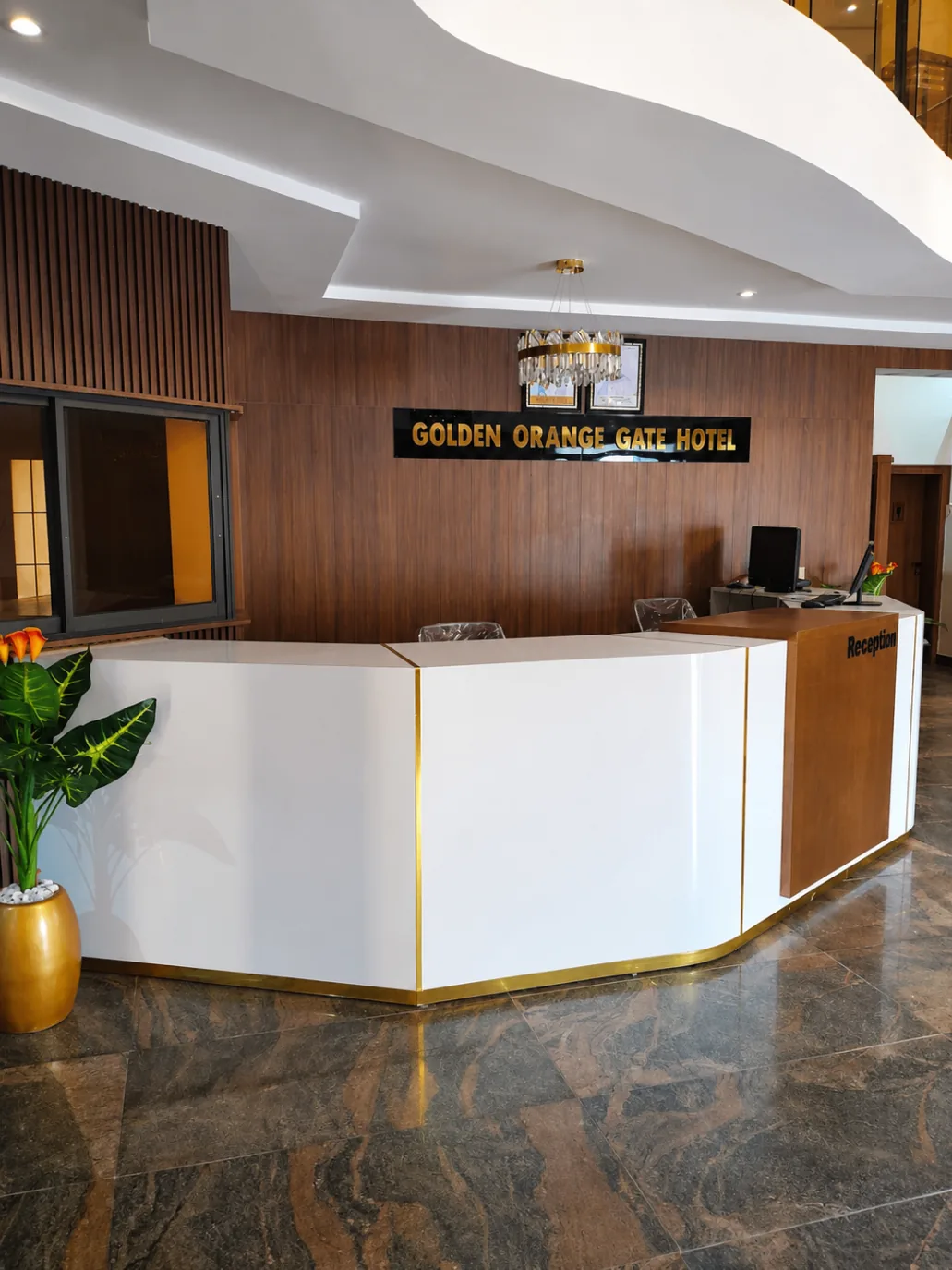 Golden Orange Gate reception desk with wood panel backdrop and chandelier